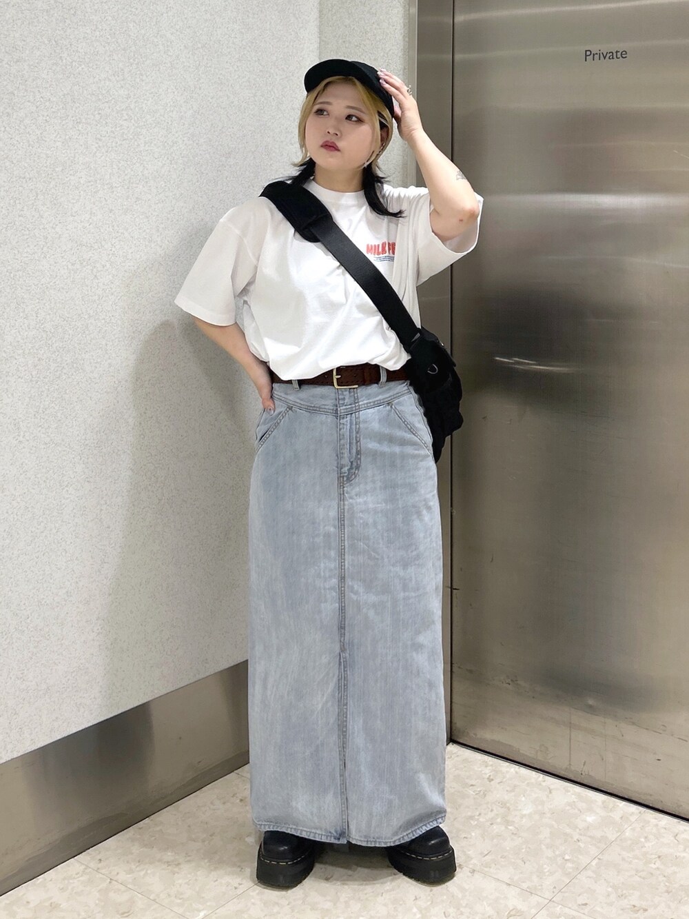 ホワイト系のTシャツ/カットソー、ブラック系のメッセンジャーバッグ、ブルー系のデニムスカートを着用したレディースの春コーディネートの2枚目の写真