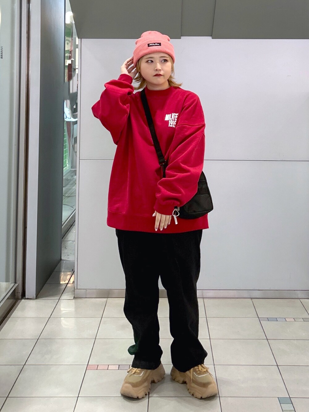 レッド系のスウェット、ピンク系のショルダーバッグ、ブラック系のデニムパンツを着用したレディースの秋コーディネートの2枚目の写真