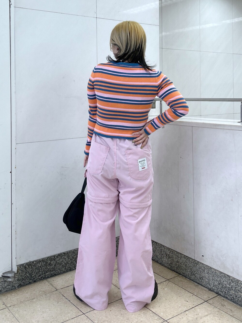 オレンジ系のカーディガン/ボレロ、ピンク系のその他パンツ、ブラック系のハンドバッグを着用したレディースの春コーディネートの5枚目の写真