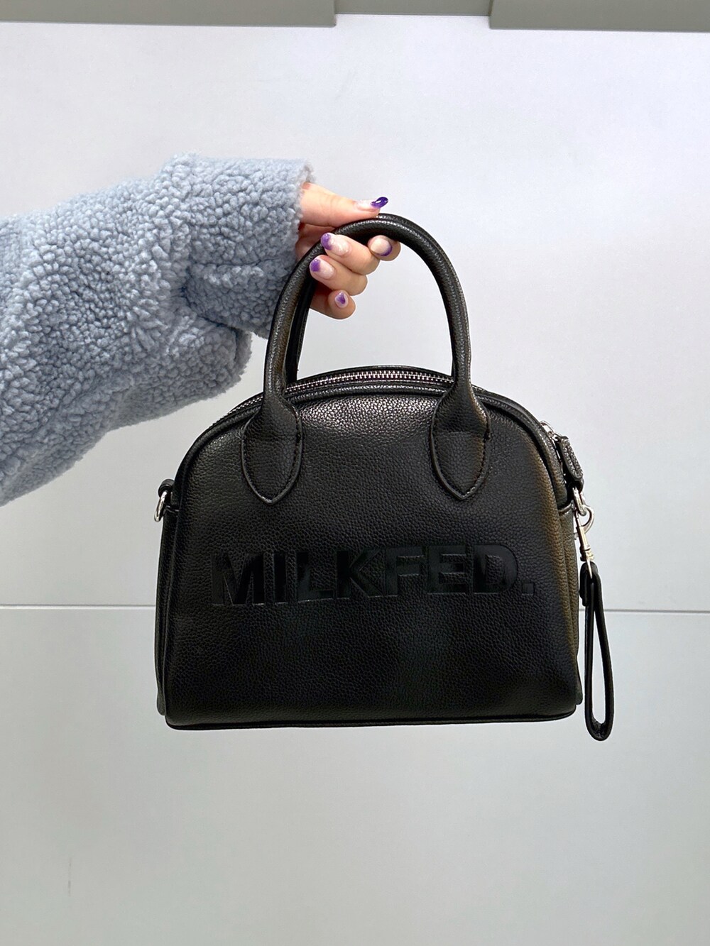 ブラック系のボストンバッグ、グリーン系のスカート、ベージュ系のスニーカーを着用したレディースの秋コーディネートの5枚目の写真