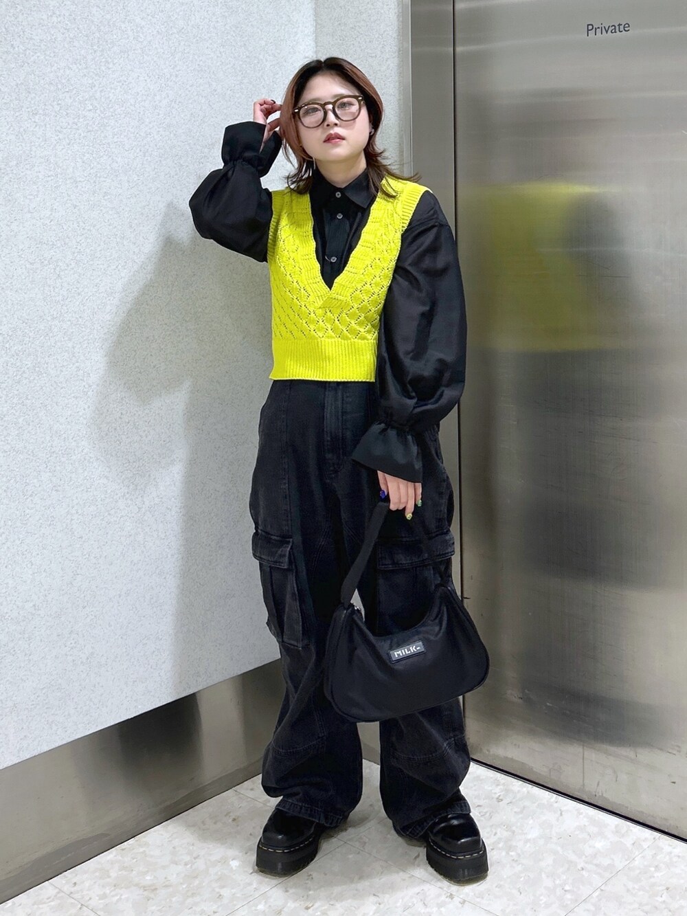 ブラック系のシャツ/ブラウス、イエロー系のベスト、ブラック系のカーゴパンツを着用したレディースの春コーディネートの3枚目の写真