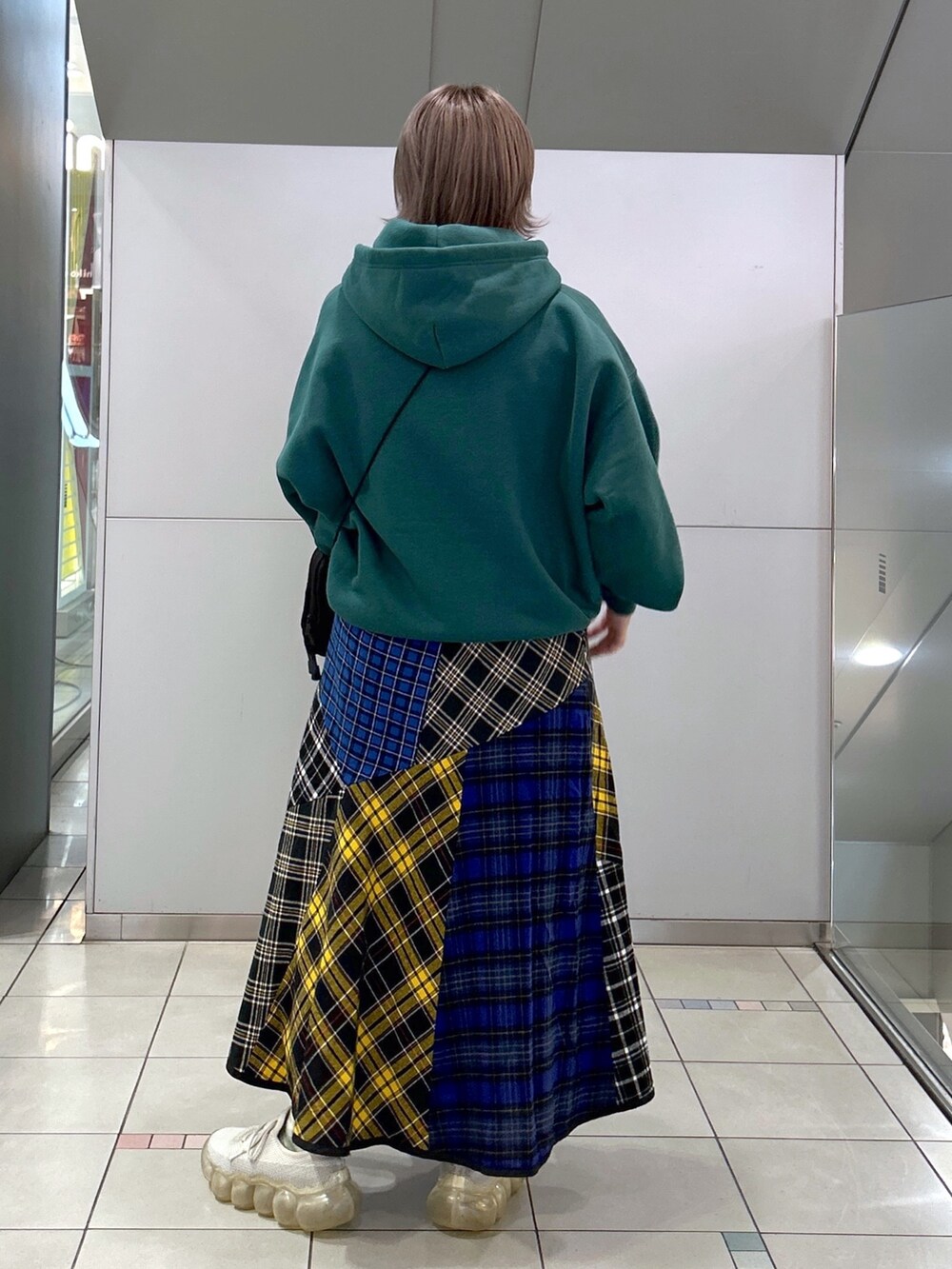 グリーン系のパーカー、グリーン系のショルダーバッグ、ブラック系のスカートを着用したレディースの秋コーディネートの2枚目の写真