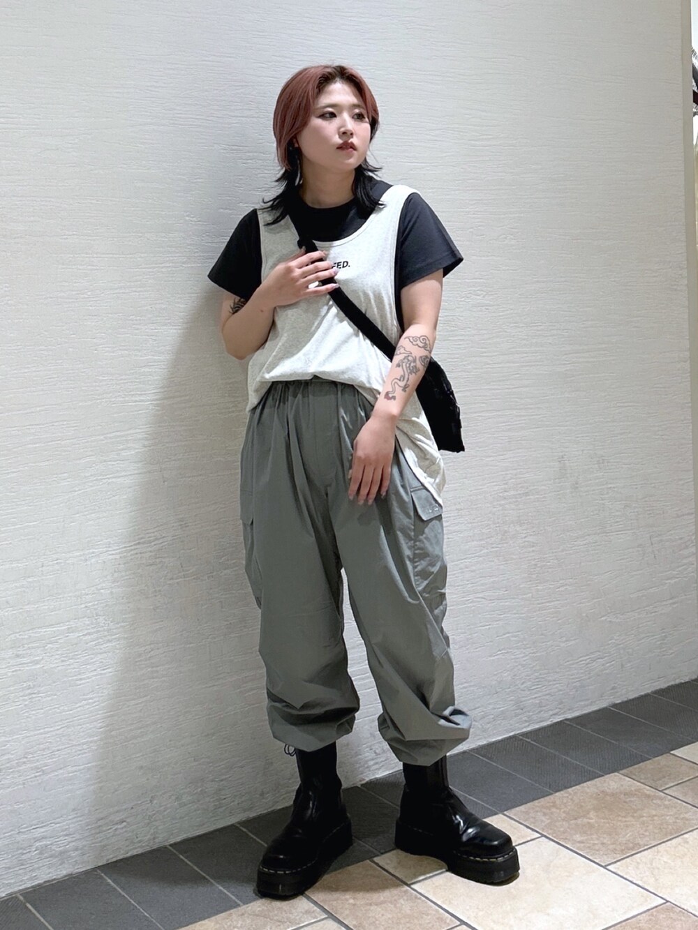 グレー系のTシャツ/カットソー、グリーン系のショルダーバッグ、ベージュ系のタンクトップを着用したレディースの春コーディネートの2枚目の写真