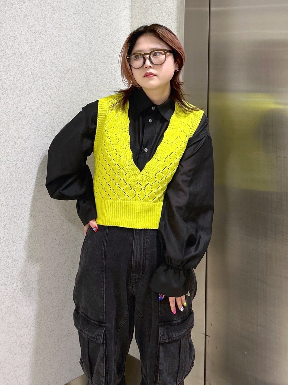 ブラック系のシャツ/ブラウス、イエロー系のベスト、ブラック系のカーゴパンツを着用したレディースの春コーディネートの6枚目の写真
