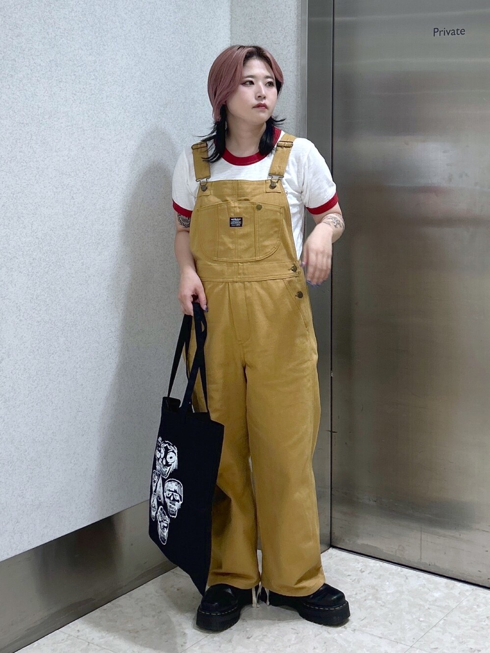 レッド系のTシャツ/カットソー、ベージュ系のサロペット/オーバーオール、ブラック系のトートバッグを着用したレディースの夏コーディネートの2枚目の写真