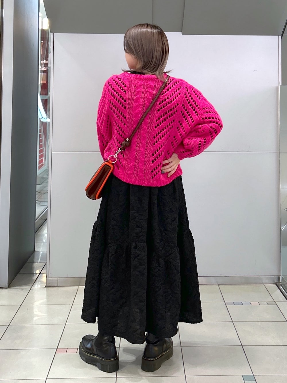 ピンク系のニット/セーター、ブラック系のワンピース、ブラウン系のショルダーバッグを着用したレディースの冬コーディネートの2枚目の写真