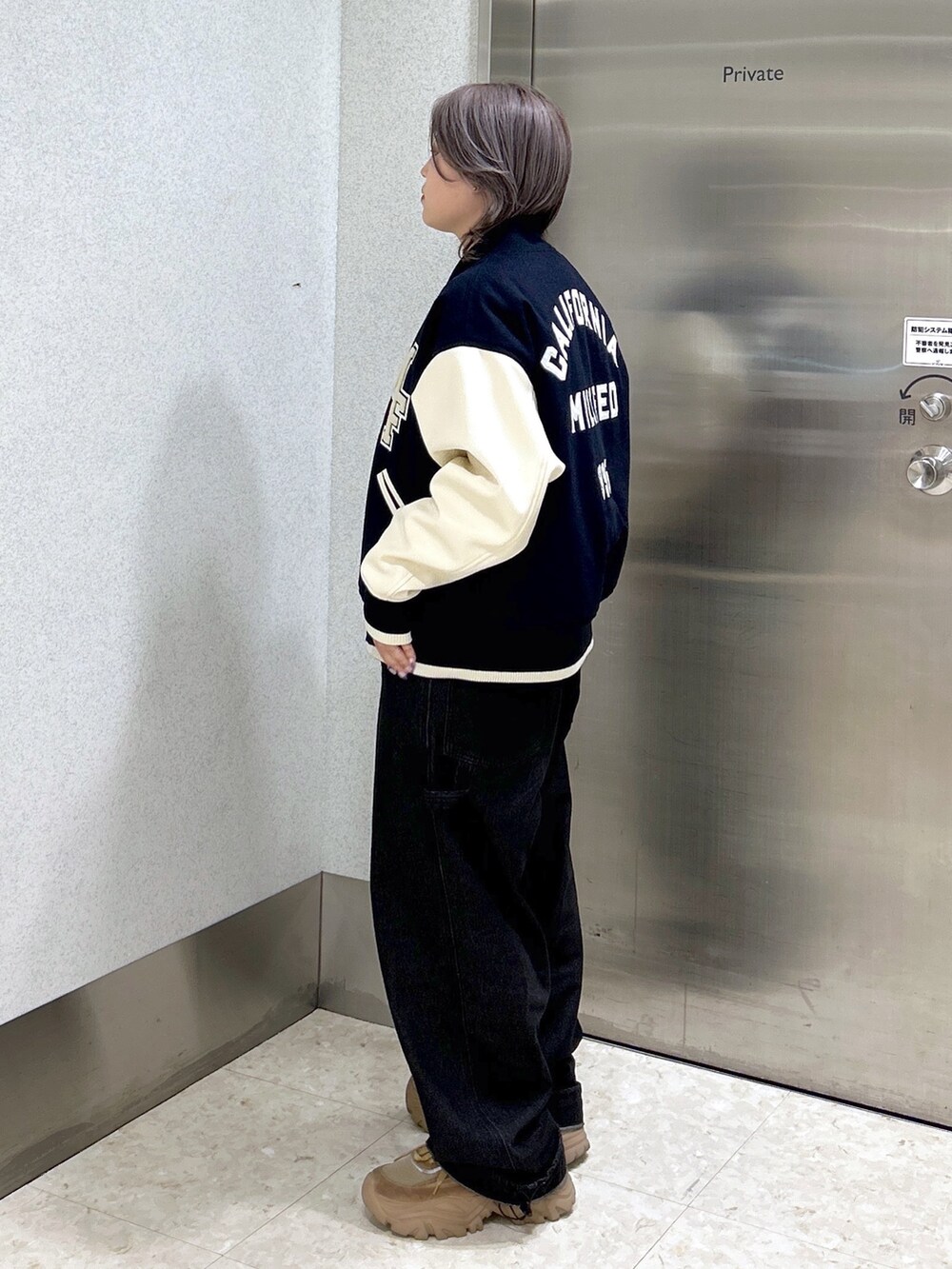 ブルー系のスタジャン、ブラック系のサロペット/オーバーオール、ベージュ系のスニーカーを着用したレディースの秋コーディネートの2枚目の写真