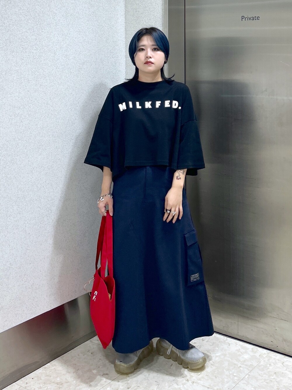 ブルー系のスカート、ブラック系のTシャツ/カットソー、レッド系のトートバッグを着用したレディースの夏コーディネートの4枚目の写真