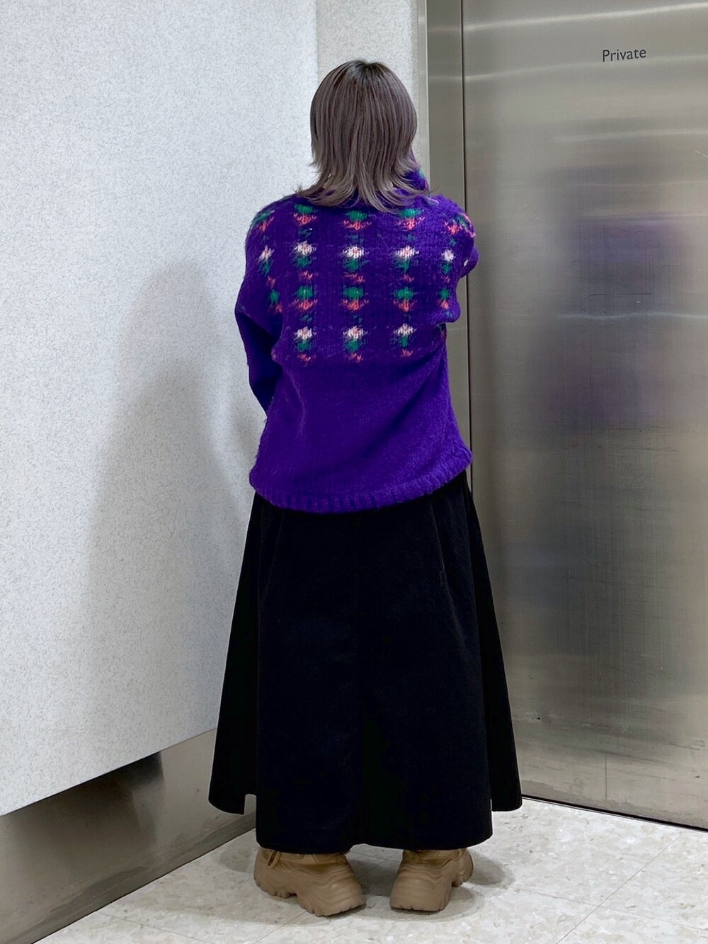 パープル系のカーディガン/ボレロ、ベージュ系のその他トップス、ブラック系のジャンパースカートを着用したレディースの冬コーディネートの2枚目の写真