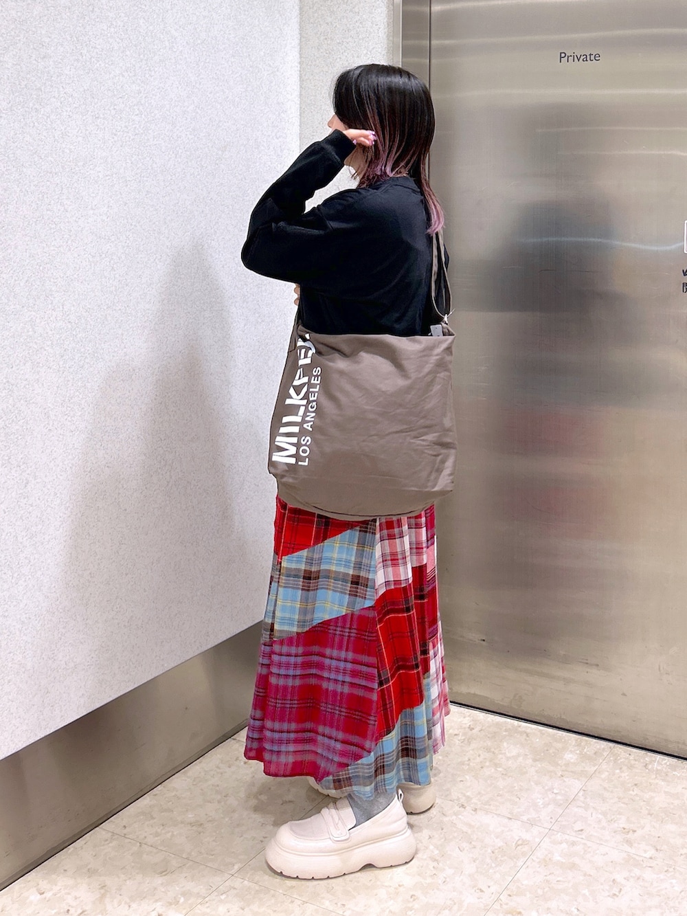 ブラック系のTシャツ/カットソー、ブラウン系のショルダーバッグ、レッド系のスカートを着用したレディースの秋コーディネートの3枚目の写真