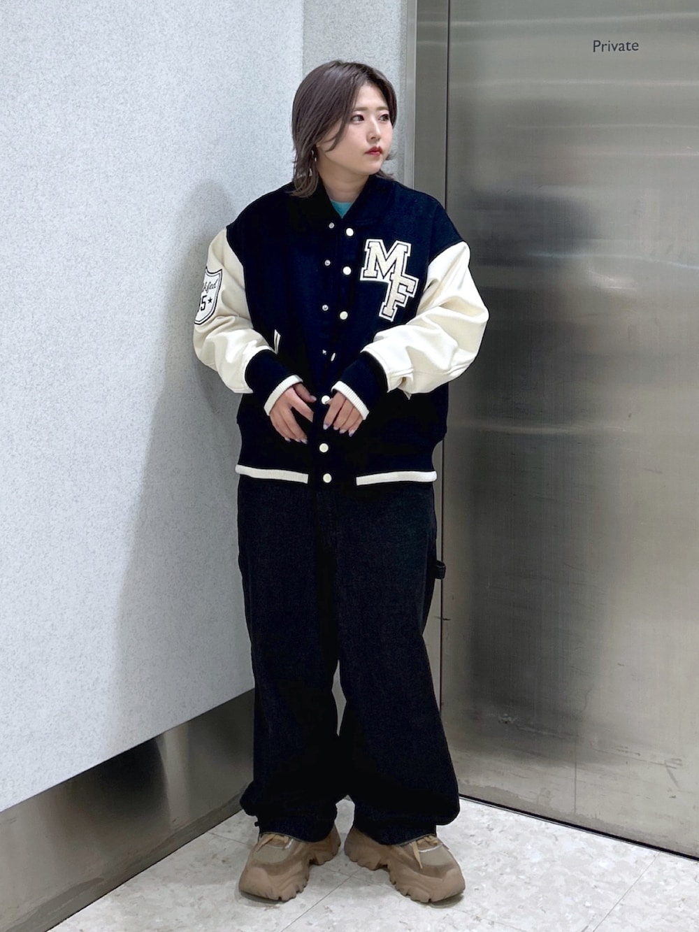 ブルー系のスタジャン、ブラック系のサロペット/オーバーオール、ベージュ系のスニーカーを着用したレディースの秋コーディネートの3枚目の写真