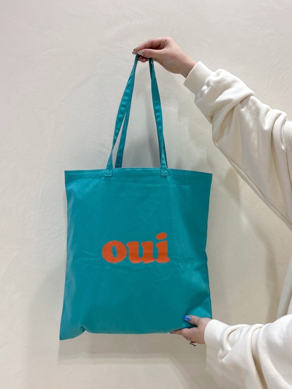 ホワイト系のパーカー、ブラック系のその他パンツ、グリーン系のトートバッグを着用したレディースの春コーディネートの7枚目の写真