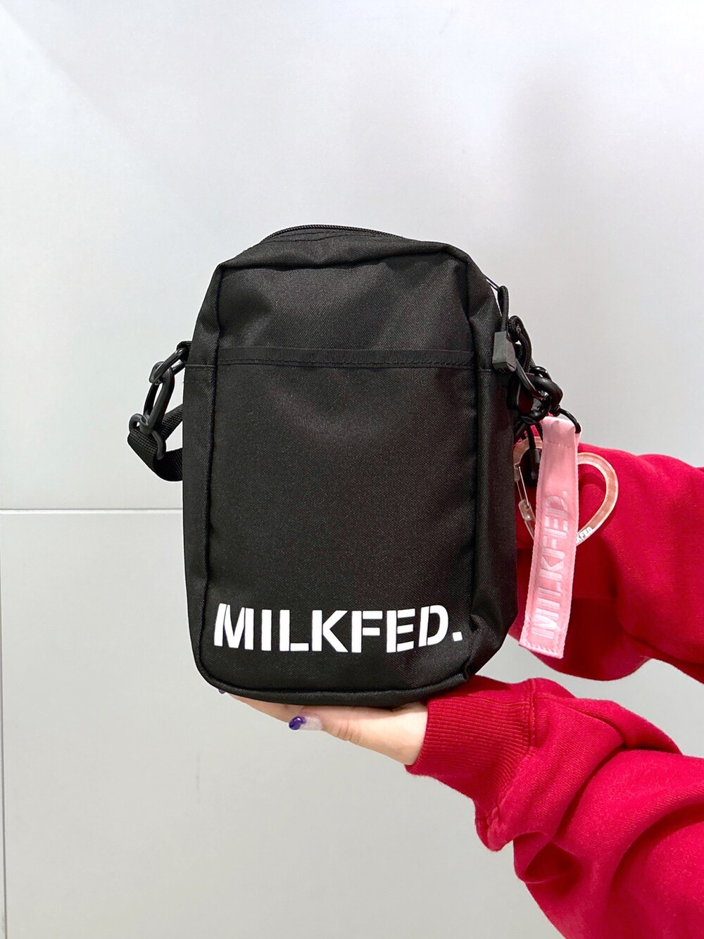 レッド系のスウェット、ピンク系のショルダーバッグ、ブラック系のデニムパンツを着用したレディースの秋コーディネートの5枚目の写真