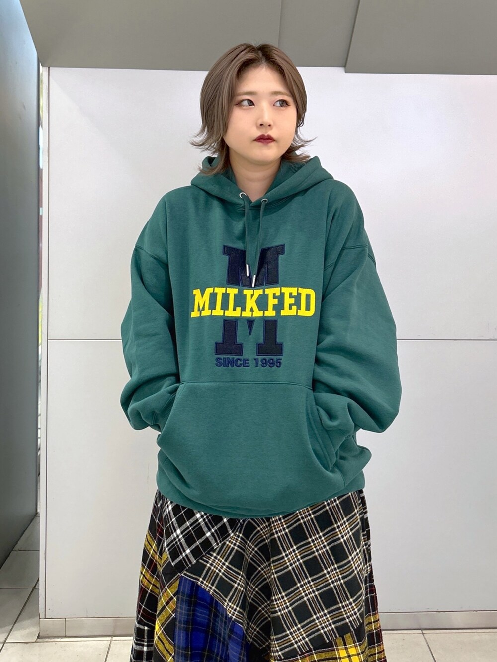 グリーン系のパーカー、グリーン系のショルダーバッグ、ブラック系のスカートを着用したレディースの秋コーディネートの3枚目の写真