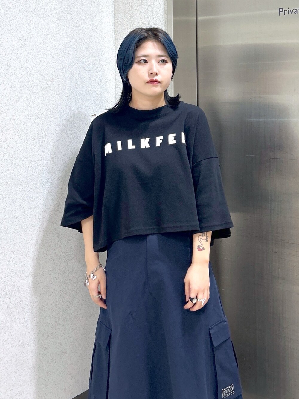 ブルー系のスカート、ブラック系のTシャツ/カットソー、レッド系のトートバッグを着用したレディースの夏コーディネートの7枚目の写真