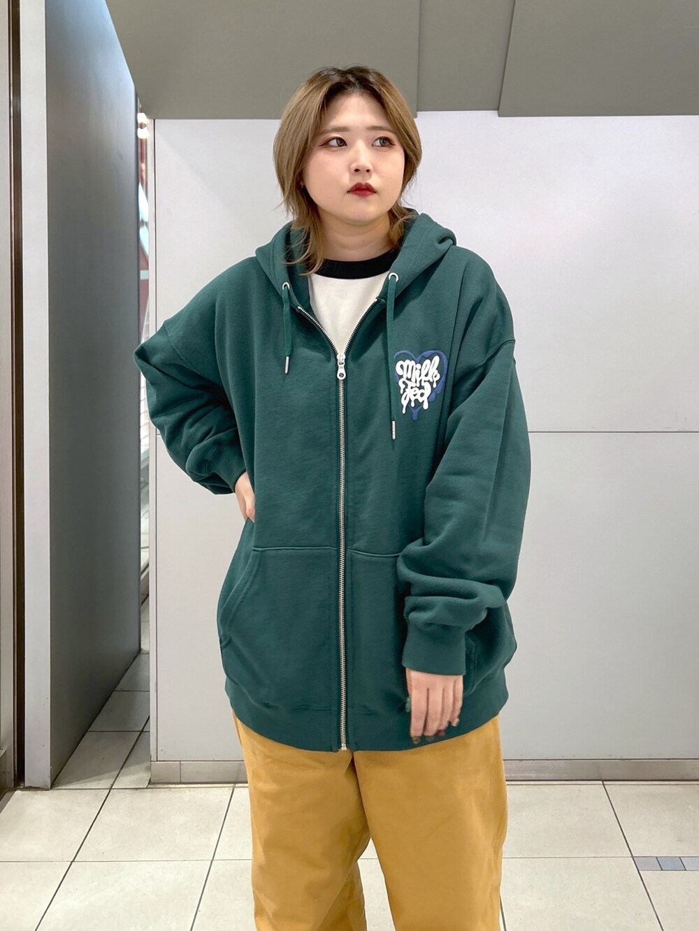 グリーン系のパーカー、ブラック系のTシャツ/カットソー、ベージュ系のサロペット/オーバーオールを着用したレディースの冬コーディネートの5枚目の写真