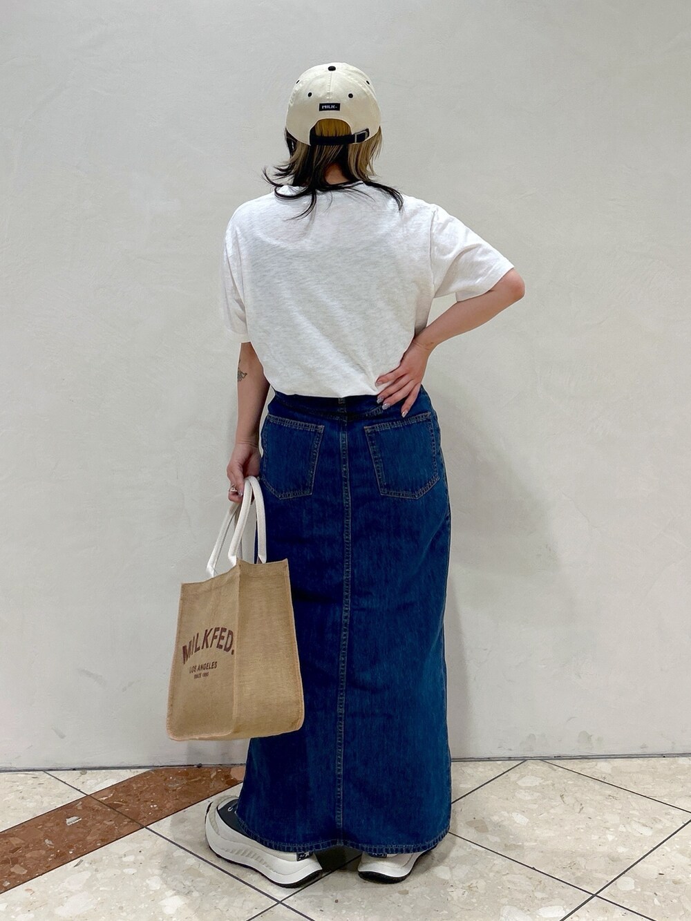 ホワイト系のTシャツ/カットソー、ブルー系のデニムスカート、ベージュ系のトートバッグを着用したレディースの春コーディネートの4枚目の写真