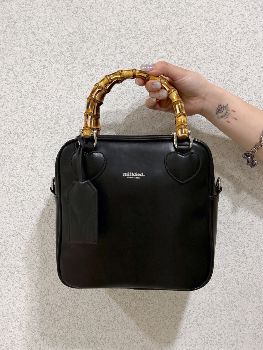 ブラック系のショルダーバッグ、ピンク系のTシャツ/カットソー、グリーン系のワンピースを着用したレディースの春コーディネートの7枚目の写真