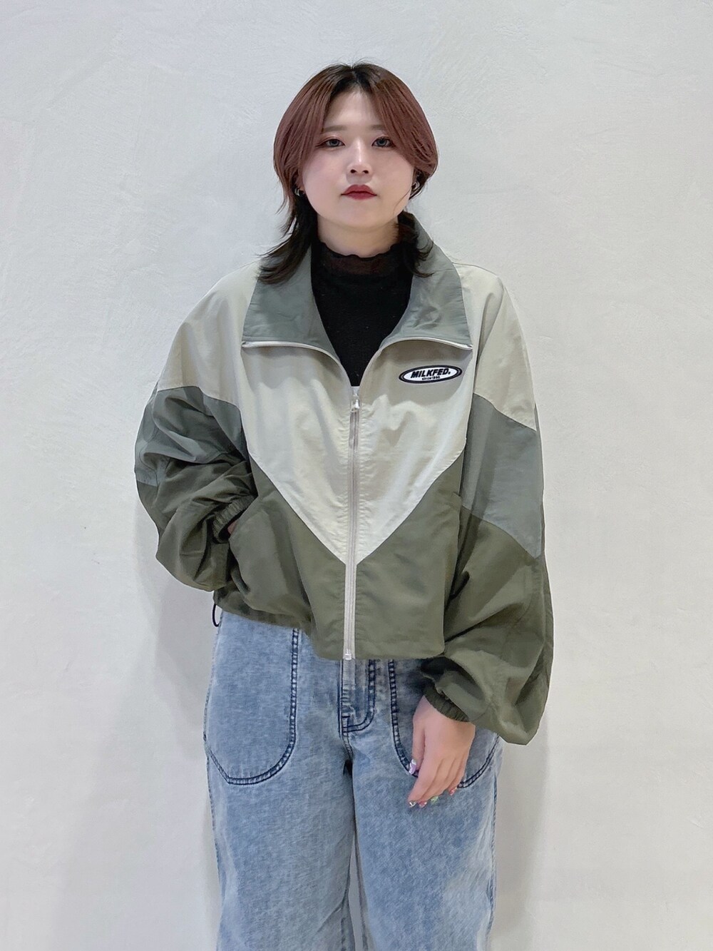 ブルー系のデニムパンツ、グリーン系のハンドバッグ、ブラック系のブーツを着用したレディースの冬コーディネートの6枚目の写真