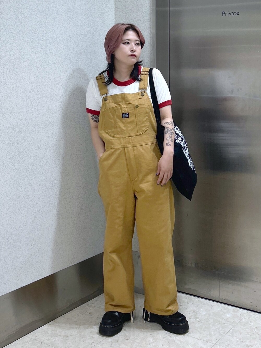 レッド系のTシャツ/カットソー、ベージュ系のサロペット/オーバーオール、ブラック系のトートバッグを着用したレディースの夏コーディネートの3枚目の写真