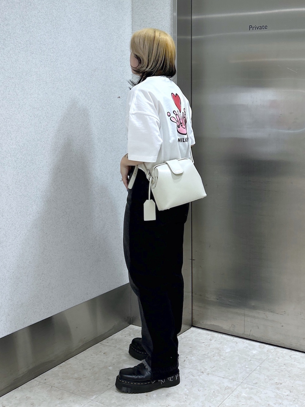 ブラック系のデニムパンツ、ホワイト系のショルダーバッグ、ブラック系のブーツを着用したレディースの春コーディネートの4枚目の写真