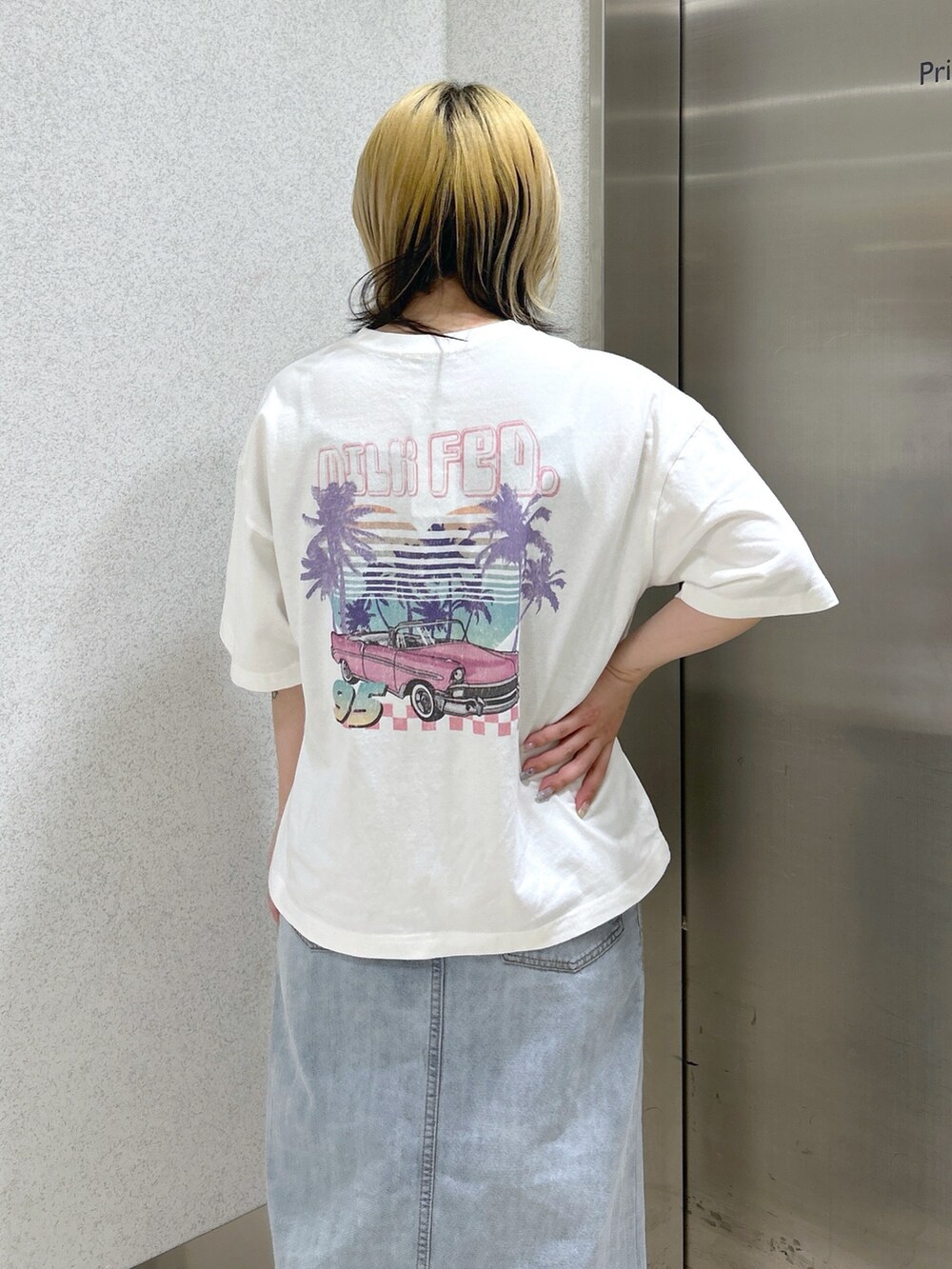 ホワイト系のTシャツ/カットソー、ブルー系のデニムスカート、グリーン系のバックパック/リュックを着用したレディースの春コーディネートの4枚目の写真