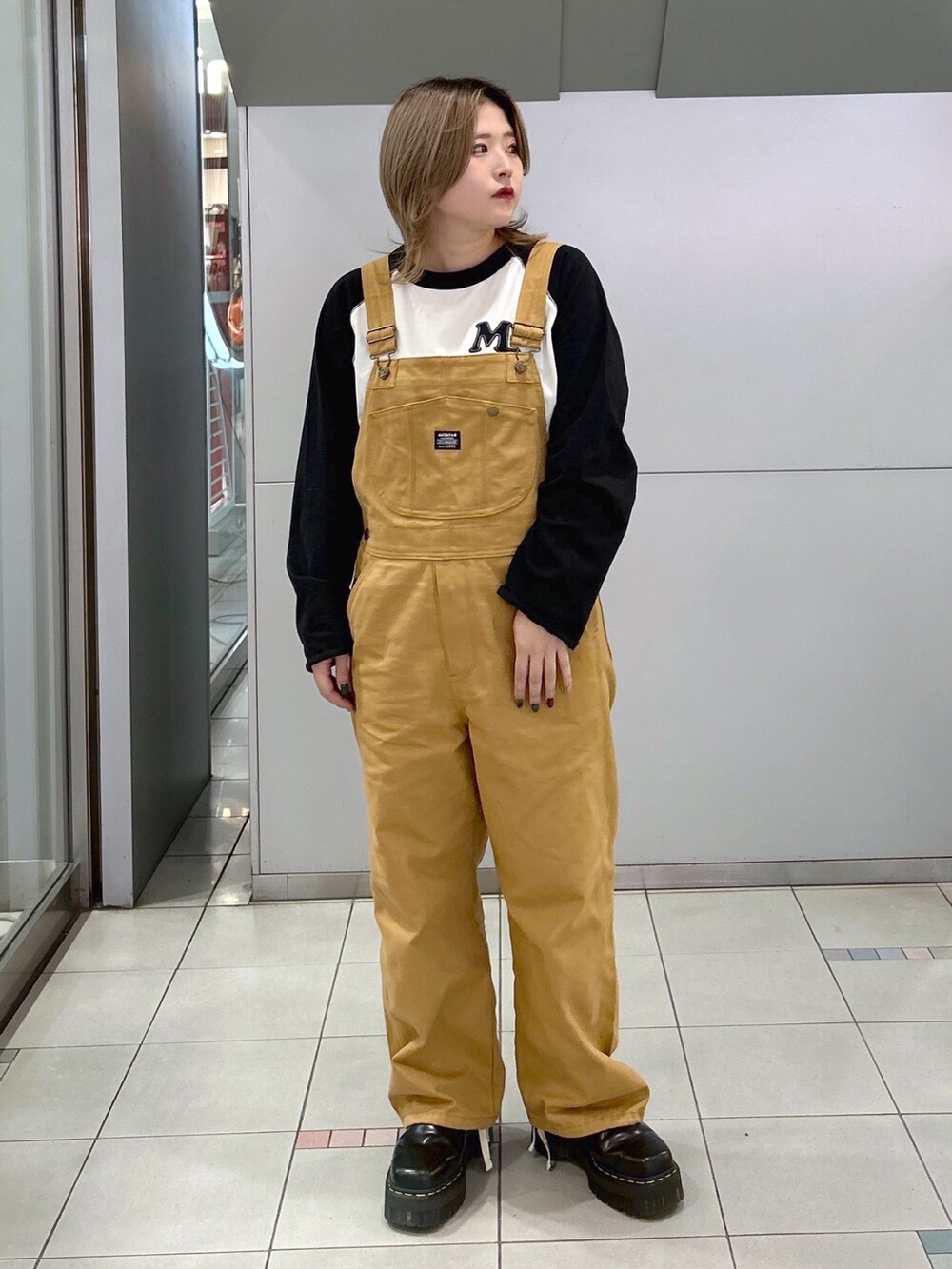 ブラック系のTシャツ/カットソー、ベージュ系のサロペット/オーバーオール、ブラック系のブーツを着用したレディースの冬コーディネートの3枚目の写真