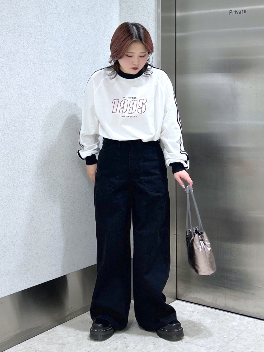 ホワイト系のTシャツ/カットソー、ブラック系のデニムパンツ、シルバー系のショルダーバッグを着用したレディースの冬コーディネートの2枚目の写真