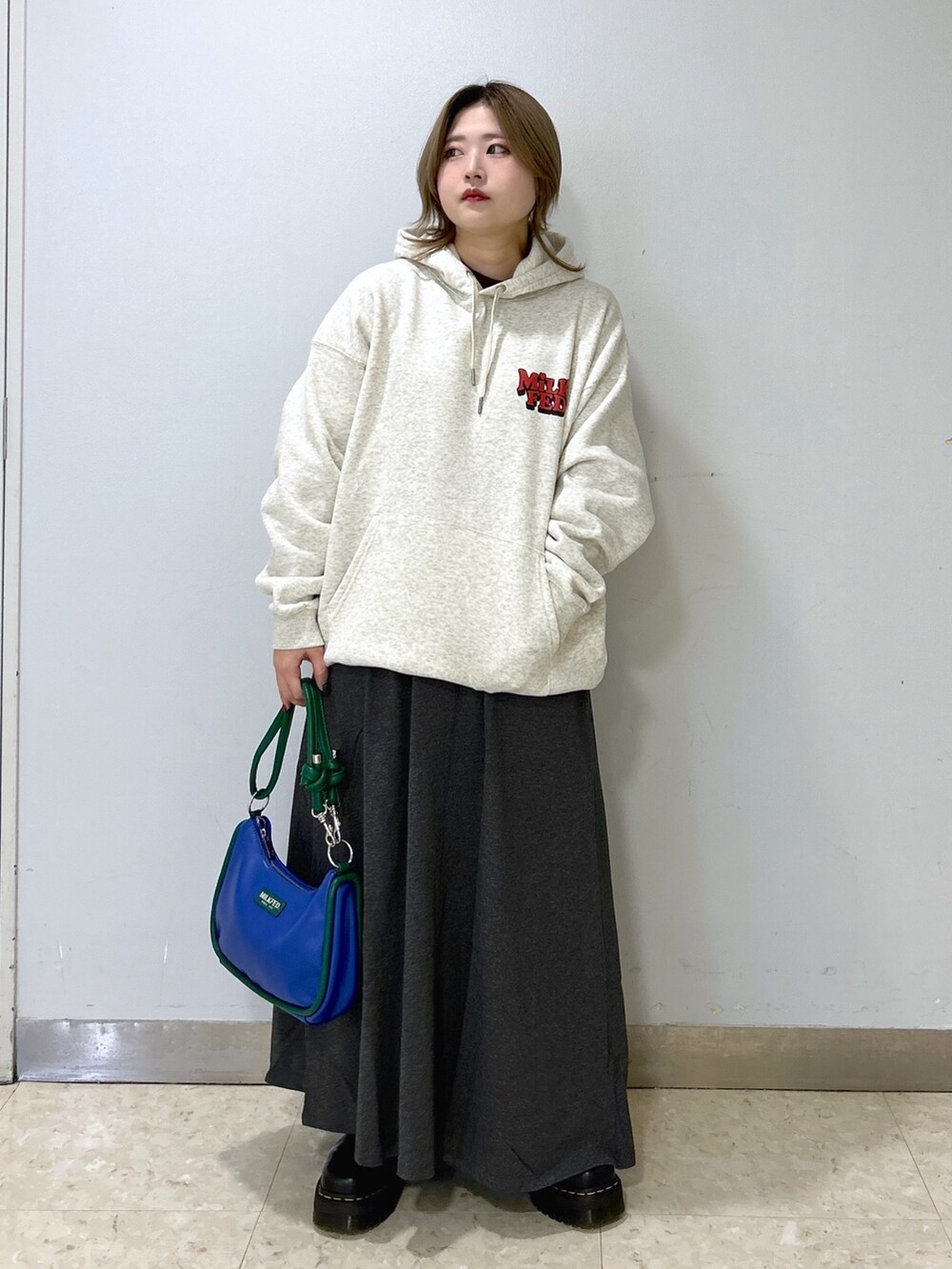 ブルー系のショルダーバッグ、ベージュ系のパーカー、グレー系のワンピースを着用したレディースの冬コーディネートの2枚目の写真