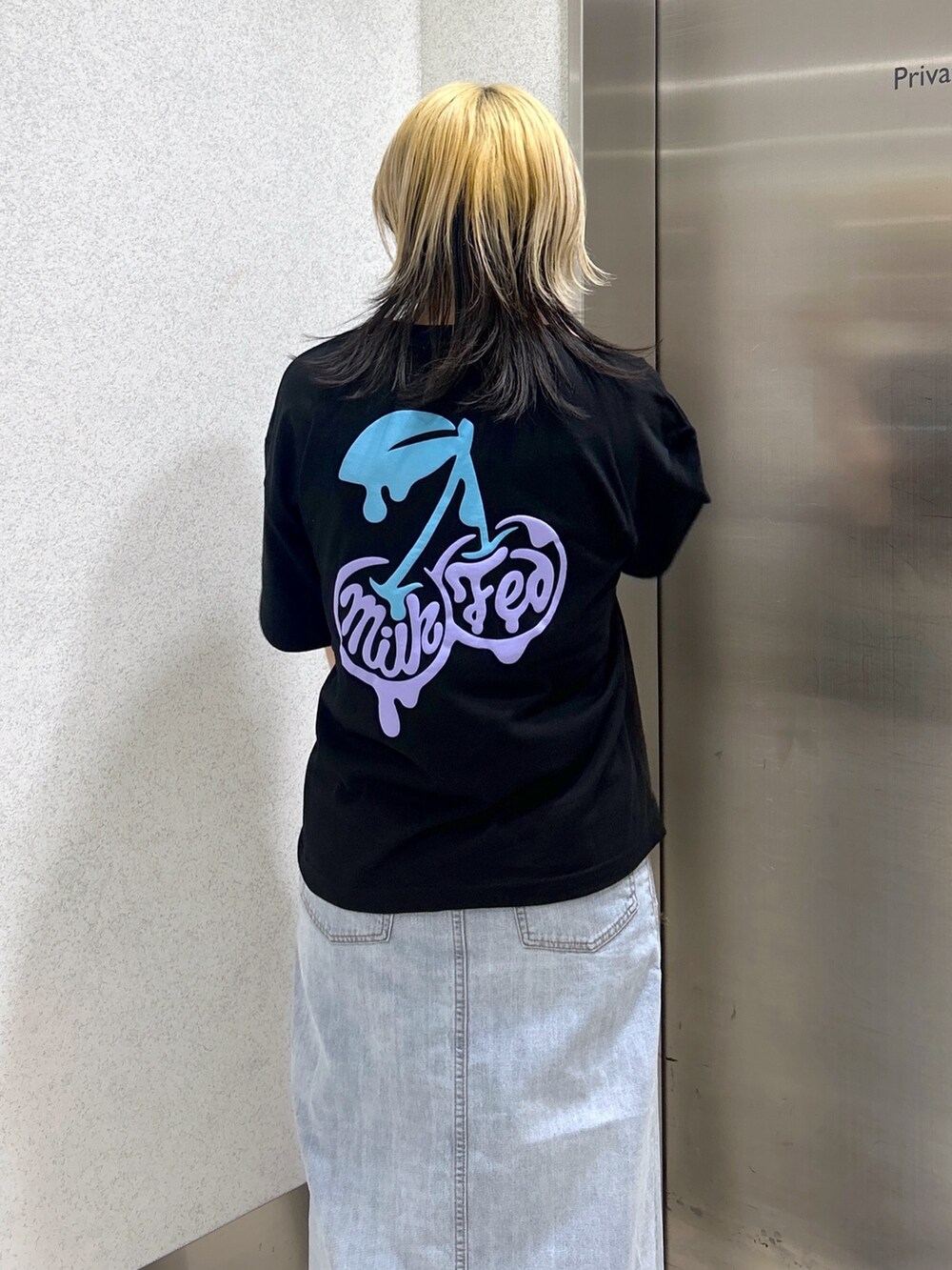 ブラック系のTシャツ/カットソー、ブルー系のデニムスカート、ブルー系のハンドバッグを着用したレディースの春コーディネートの4枚目の写真