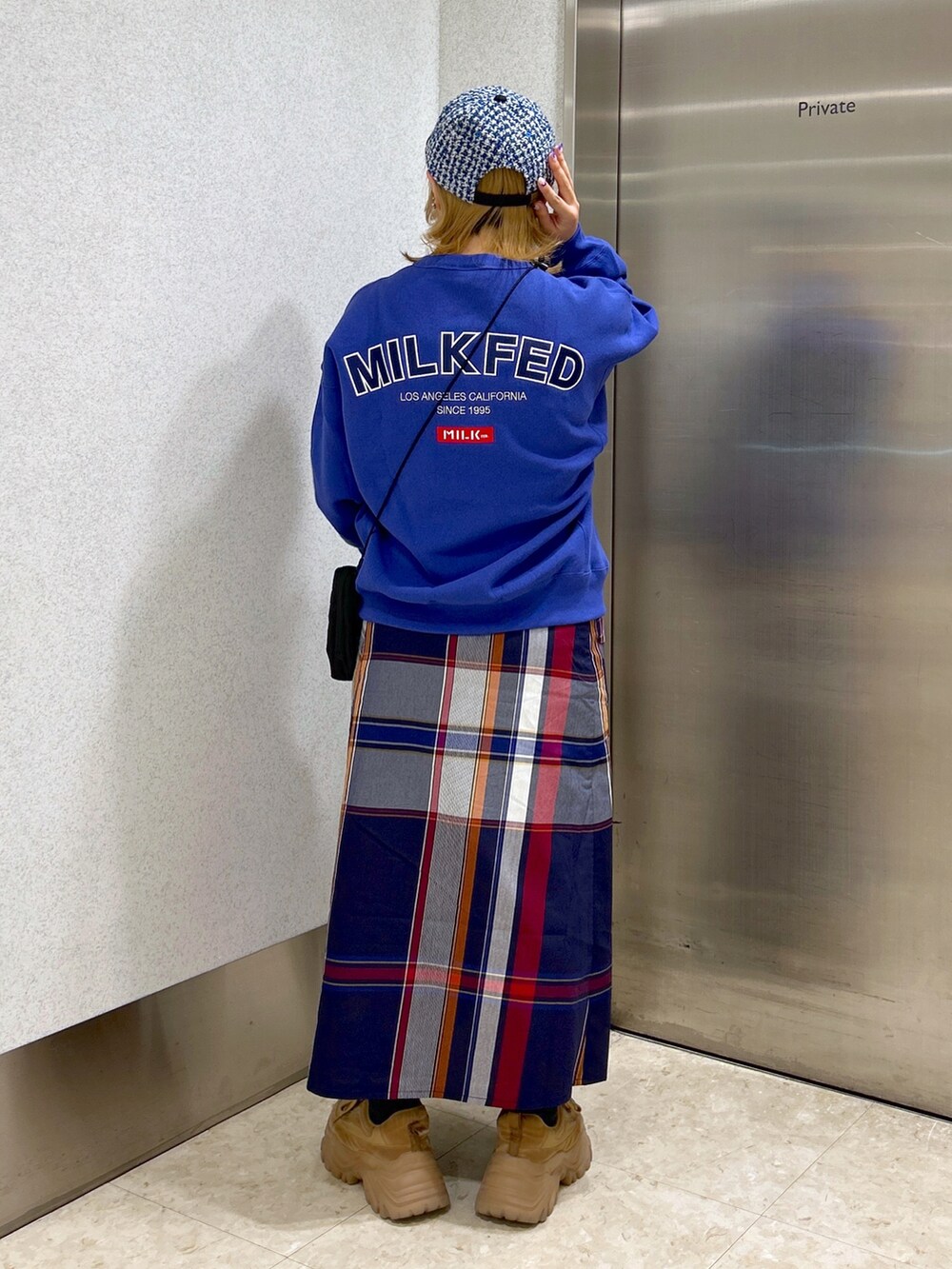 ブルー系のスウェット、ブルー系のスカート、ベージュ系のスニーカーを着用したレディースの秋コーディネートの2枚目の写真