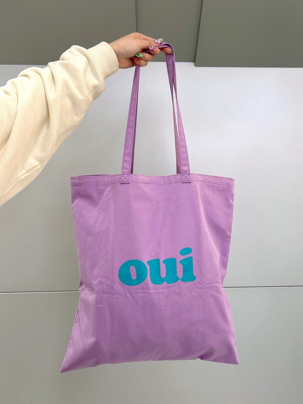 ホワイト系のスウェット、ブラック系のデニムパンツ、パープル系のトートバッグを着用したレディースの冬コーディネートの6枚目の写真