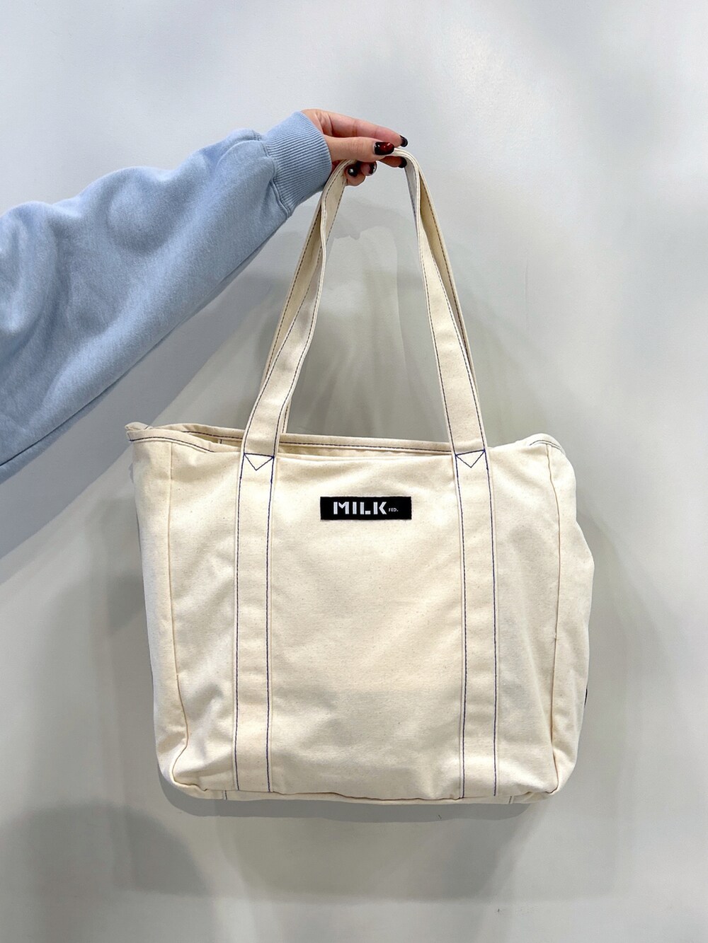 ブルー系のスウェット、ブルー系のトートバッグ、ブラック系のスカートを着用したレディースの秋コーディネートの5枚目の写真