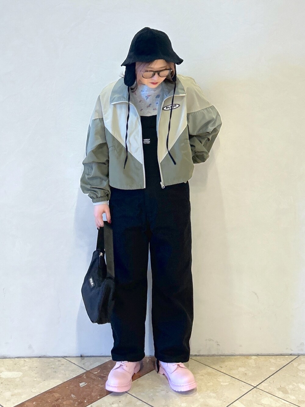 グレー系のTシャツ/カットソー、ベージュ系のナイロンジャケット、ブラック系のサロペット/オーバーオールを着用したレディースの春コーディネートの2枚目の写真