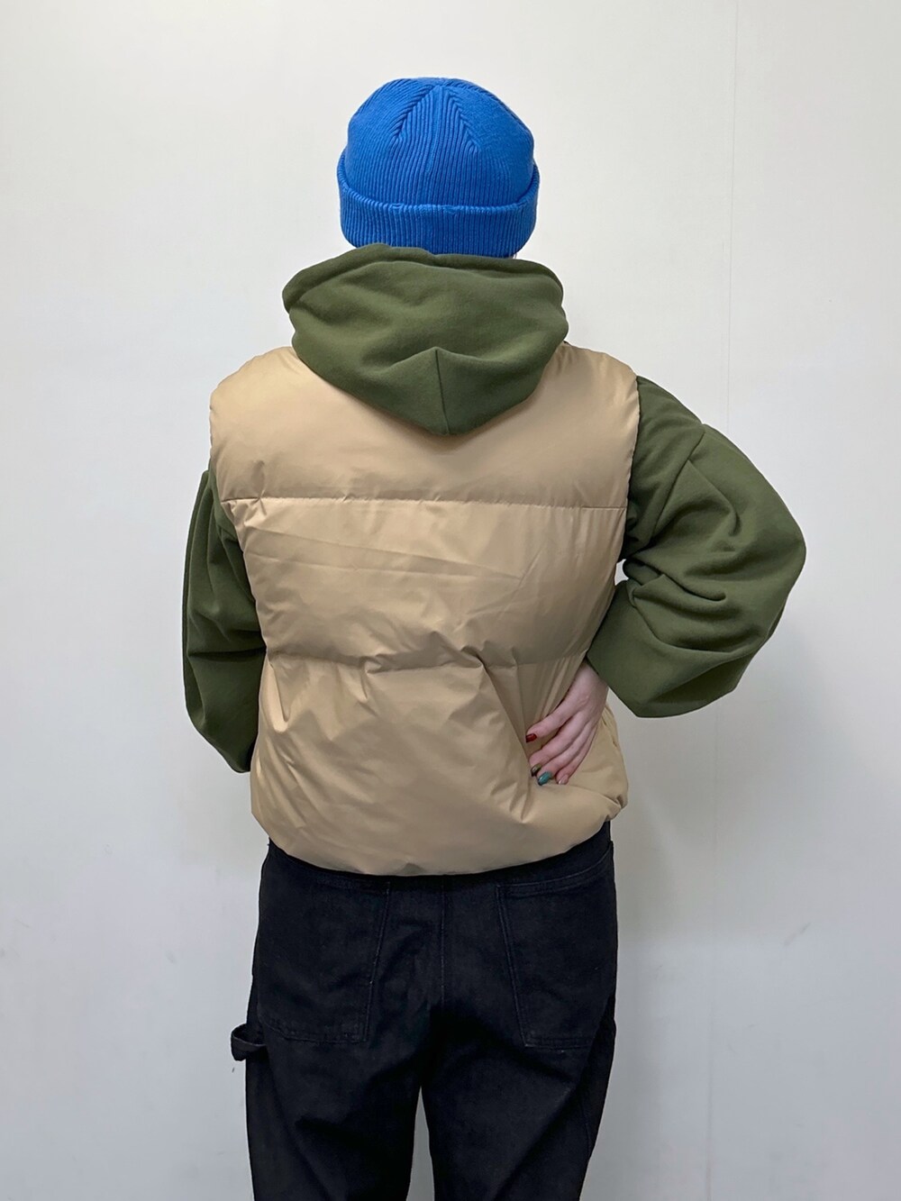 ベージュ系のダウンベスト、グリーン系のパーカー、ブラック系のサロペット/オーバーオールを着用したレディースの冬コーディネートの5枚目の写真