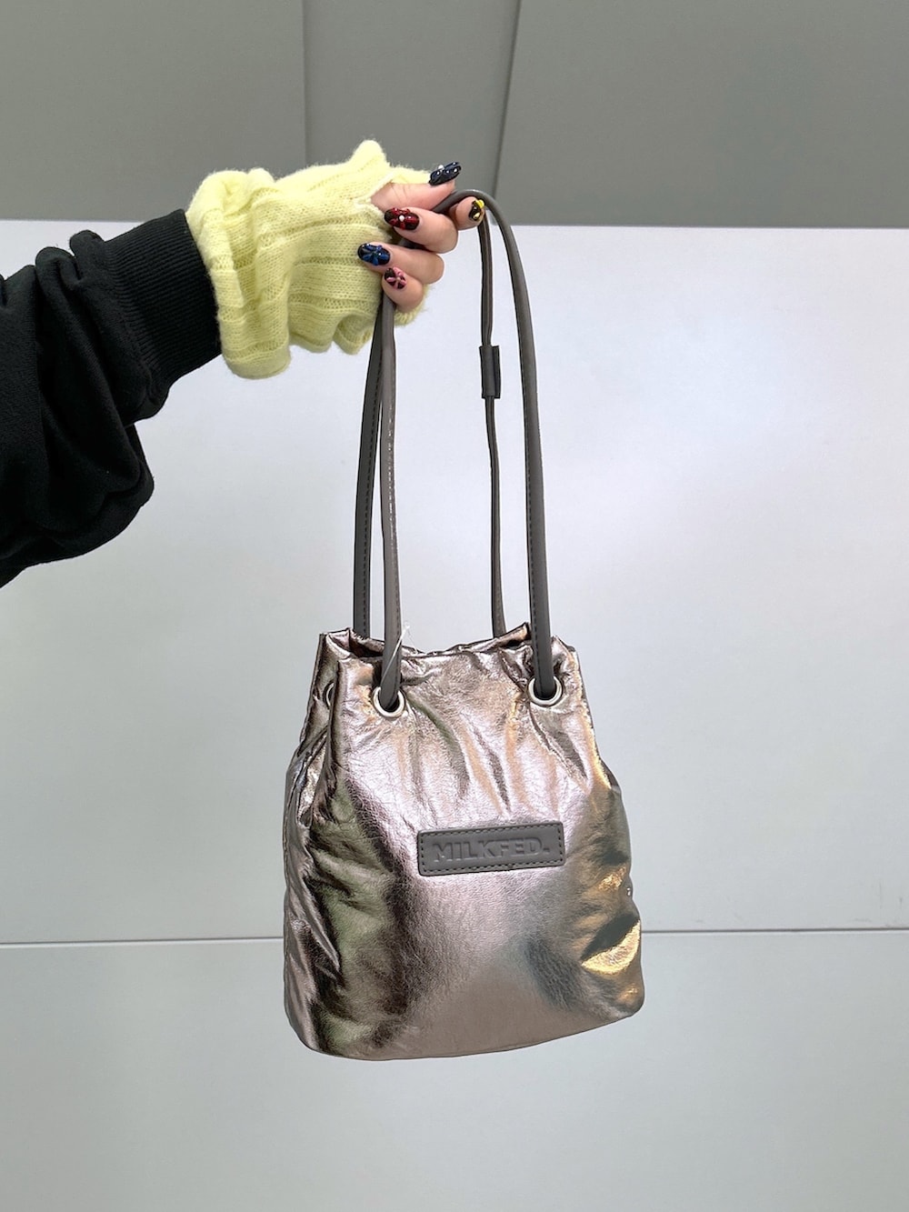 ブラック系のスウェット、グリーン系のジャンパースカート、シルバー系のショルダーバッグを着用したレディースの冬コーディネートの5枚目の写真