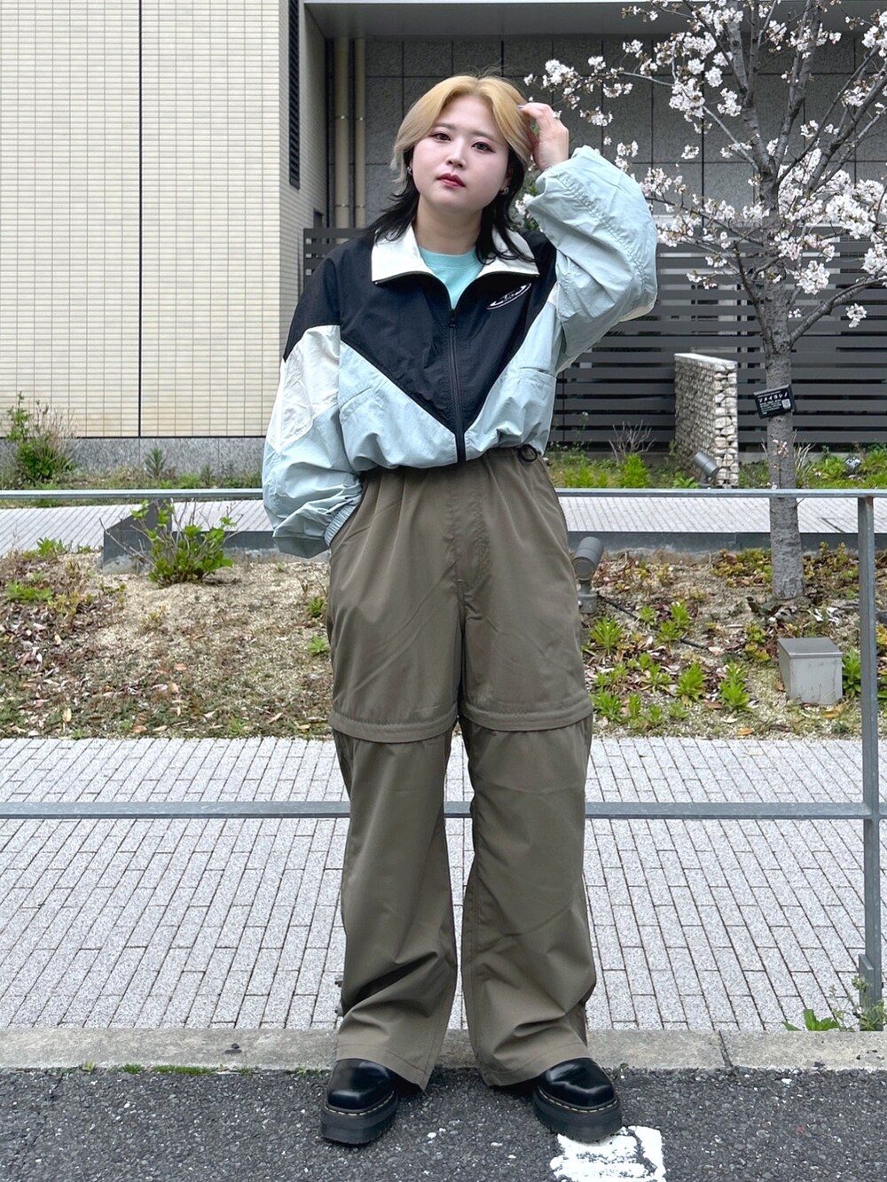 ブラック系のナイロンジャケット、グリーン系のTシャツ/カットソー、ブラック系のブーツを着用したレディースの春コーディネートの3枚目の写真