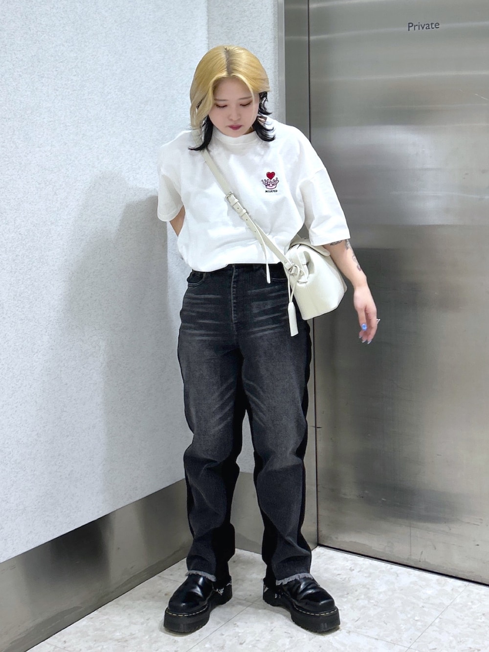 ブラック系のデニムパンツ、ホワイト系のショルダーバッグ、ブラック系のブーツを着用したレディースの春コーディネートの3枚目の写真