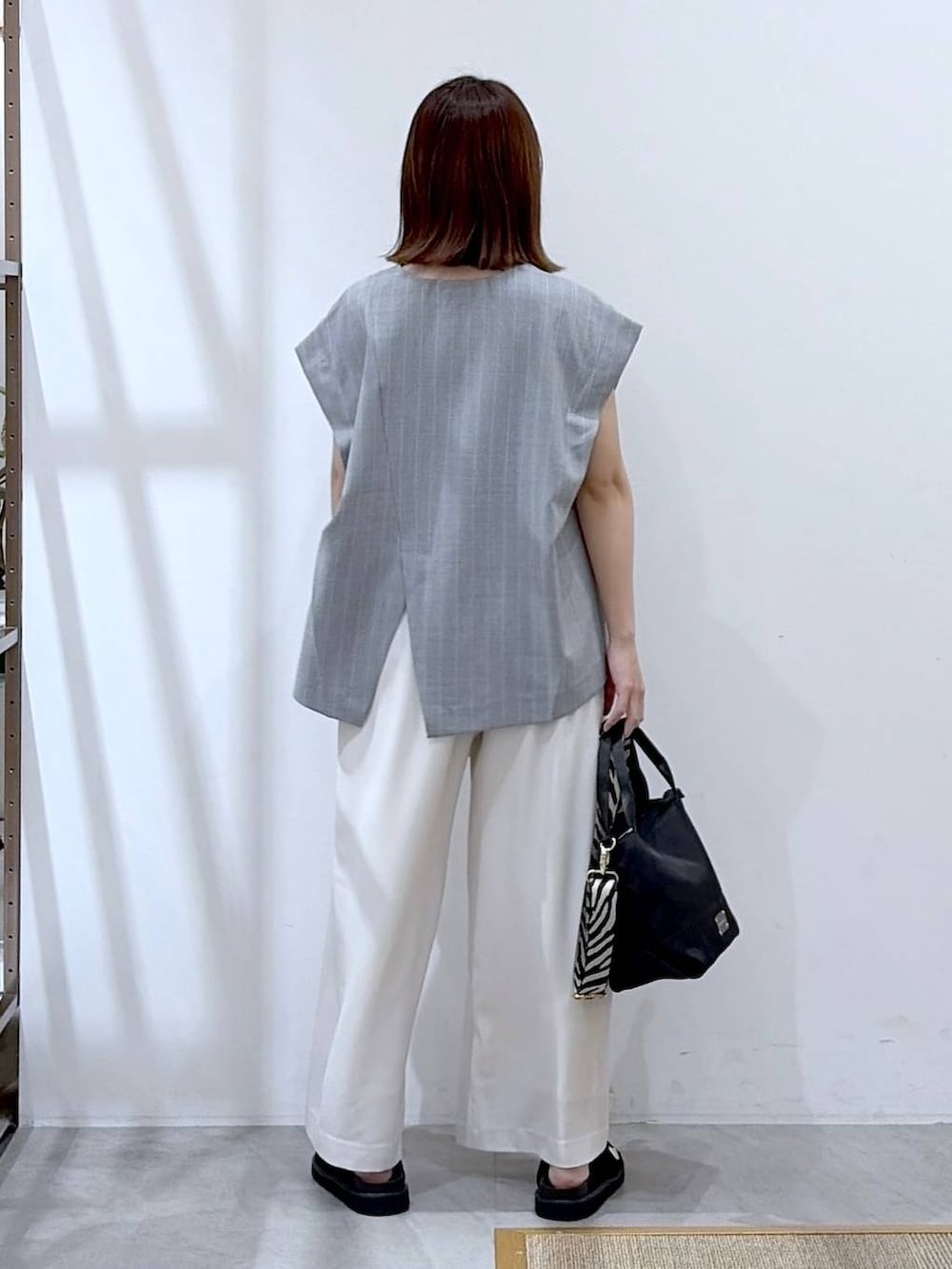 ブラック系のショルダーバッグ、ホワイト系のその他パンツ、グレー系のシャツ/ブラウスを着用したレディースの夏コーディネートの4枚目の写真