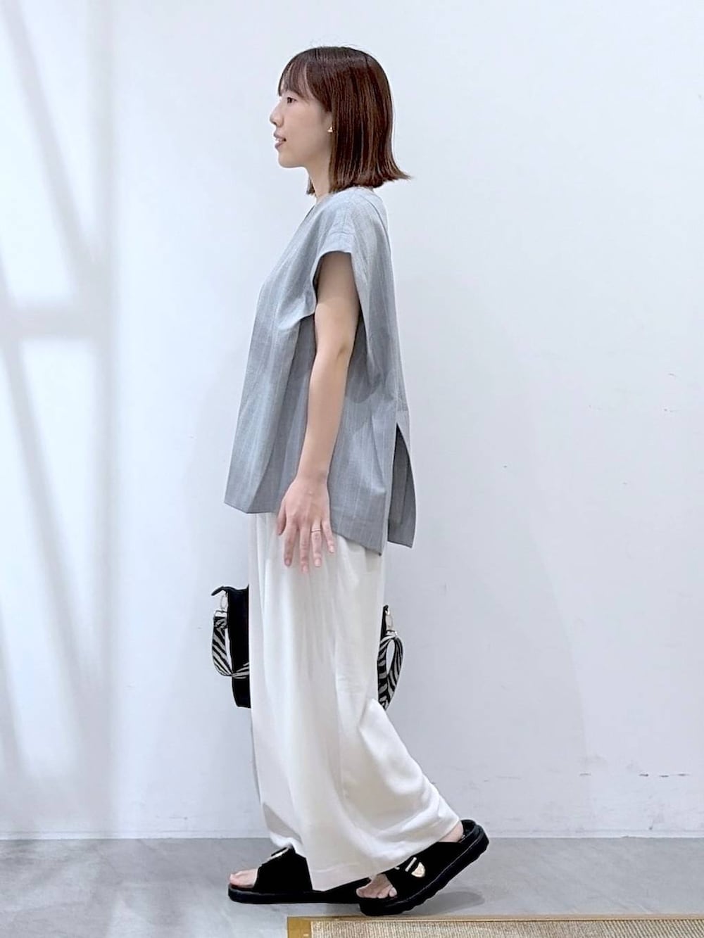 ブラック系のショルダーバッグ、ホワイト系のその他パンツ、グレー系のシャツ/ブラウスを着用したレディースの夏コーディネートの3枚目の写真