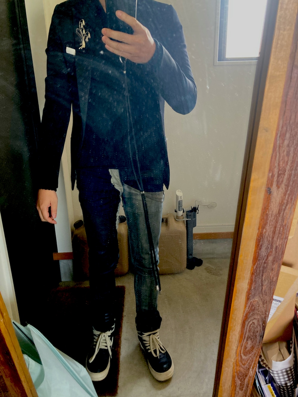 ブラック系のテーラードジャケット、ブラック系のニット/セーター、ブルー系のデニムパンツを着用したメンズの冬コーディネートの2枚目の写真