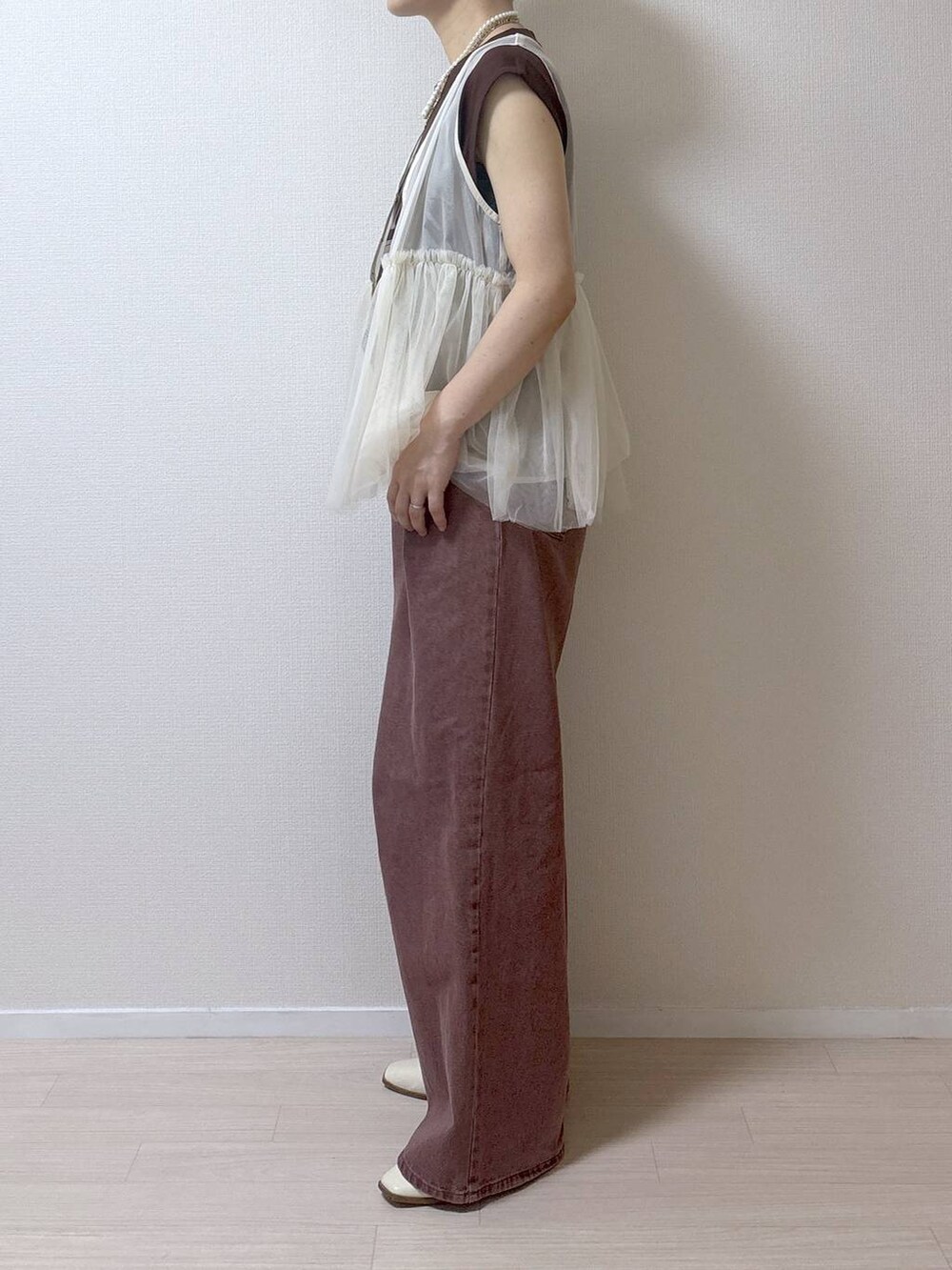 ベージュ系のベスト、ブラウン系のデニムパンツを着用したレディースの夏コーディネートの7枚目の写真