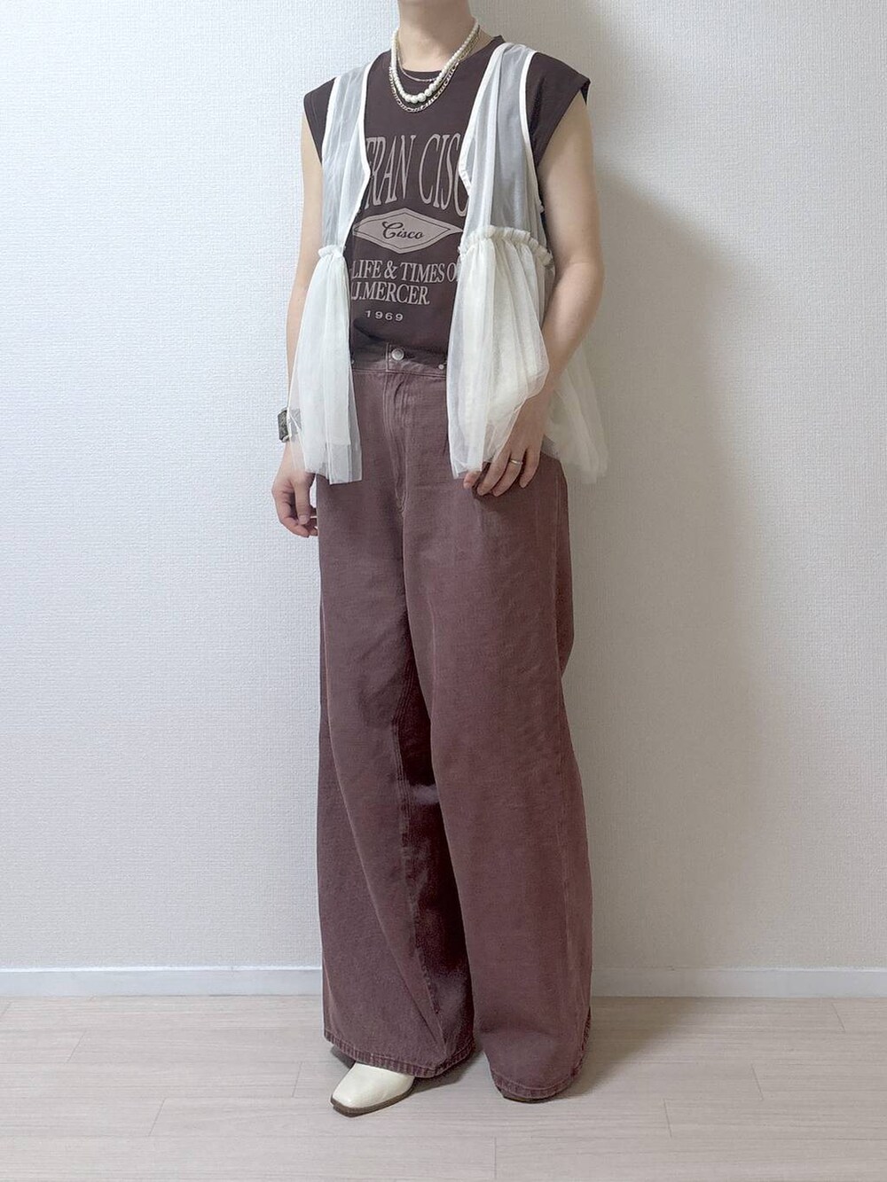 ベージュ系のベスト、ブラウン系のデニムパンツを着用したレディースの夏コーディネートの8枚目の写真