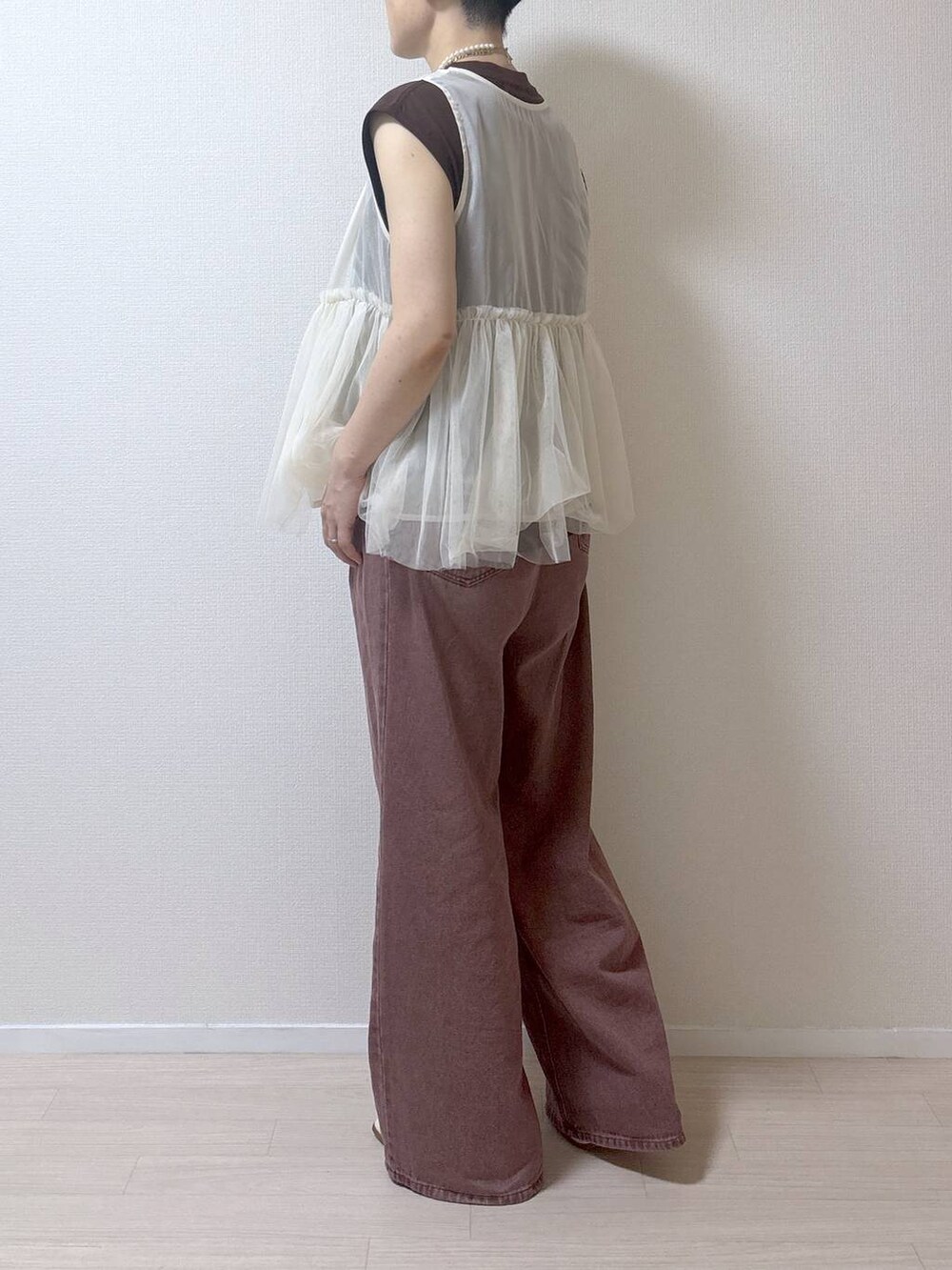 ベージュ系のベスト、ブラウン系のデニムパンツを着用したレディースの夏コーディネートの6枚目の写真