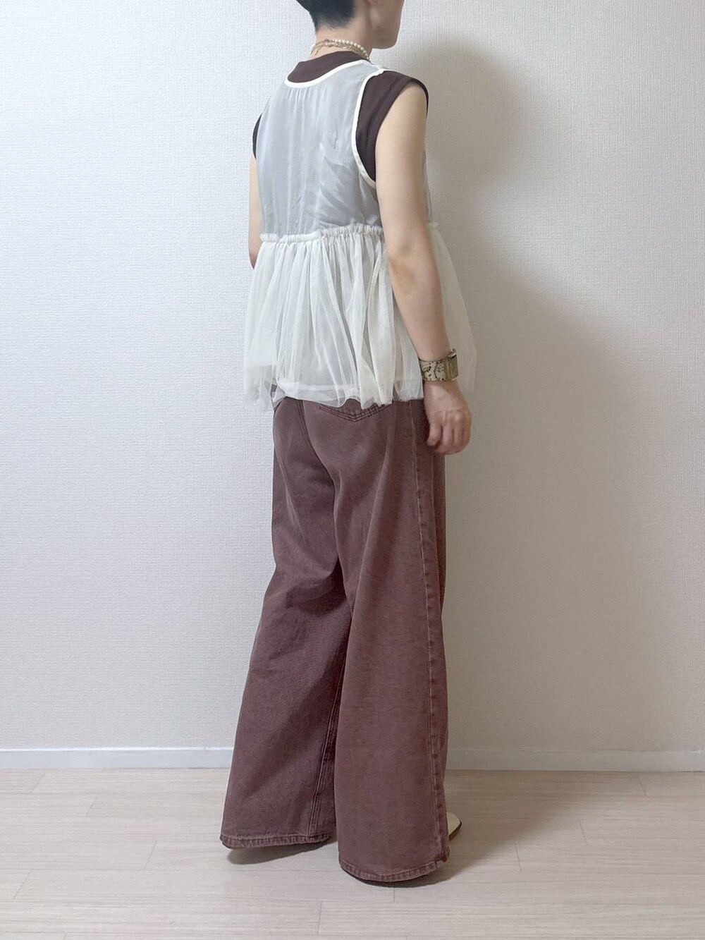 ベージュ系のベスト、ブラウン系のデニムパンツを着用したレディースの夏コーディネートの4枚目の写真