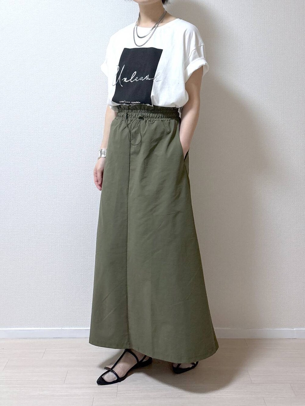 ブラック系のサンダル、ホワイト系のTシャツ/カットソー、グリーン系のスカートを着用したレディースの春コーディネートの7枚目の写真