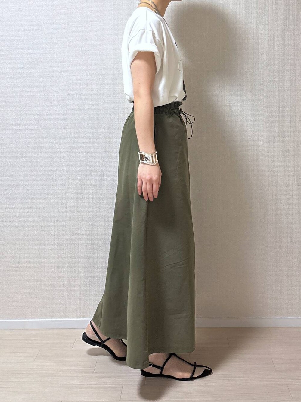 ブラック系のサンダル、ホワイト系のTシャツ/カットソー、グリーン系のスカートを着用したレディースの春コーディネートの2枚目の写真