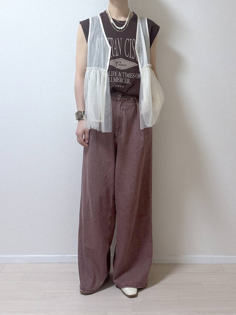 ベージュ系のベスト、ブラウン系のデニムパンツを着用したレディースの夏コーディネートの9枚目の写真