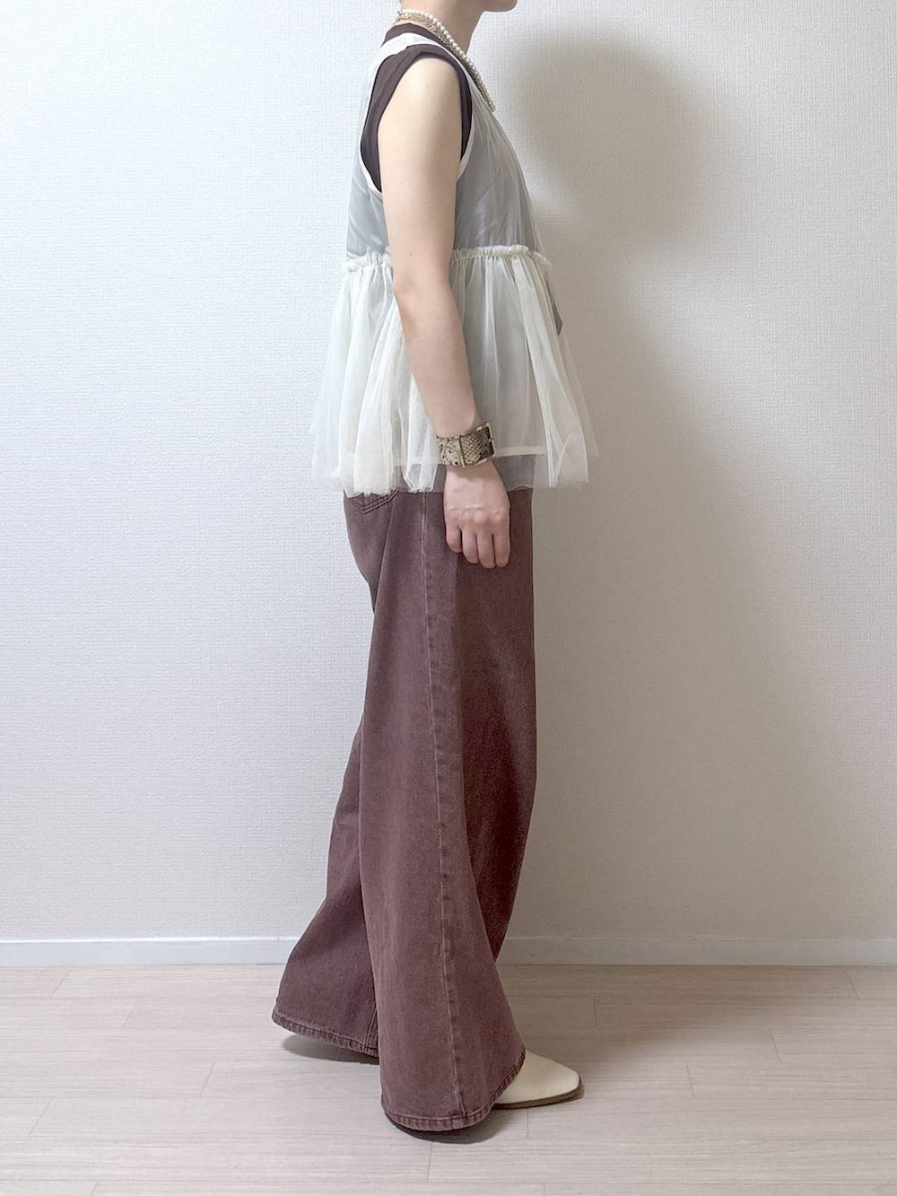 ベージュ系のベスト、ブラウン系のデニムパンツを着用したレディースの夏コーディネートの3枚目の写真