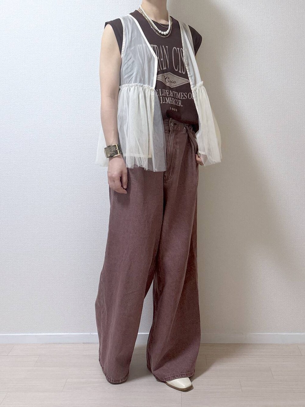 ベージュ系のベスト、ブラウン系のデニムパンツを着用したレディースの夏コーディネートの2枚目の写真